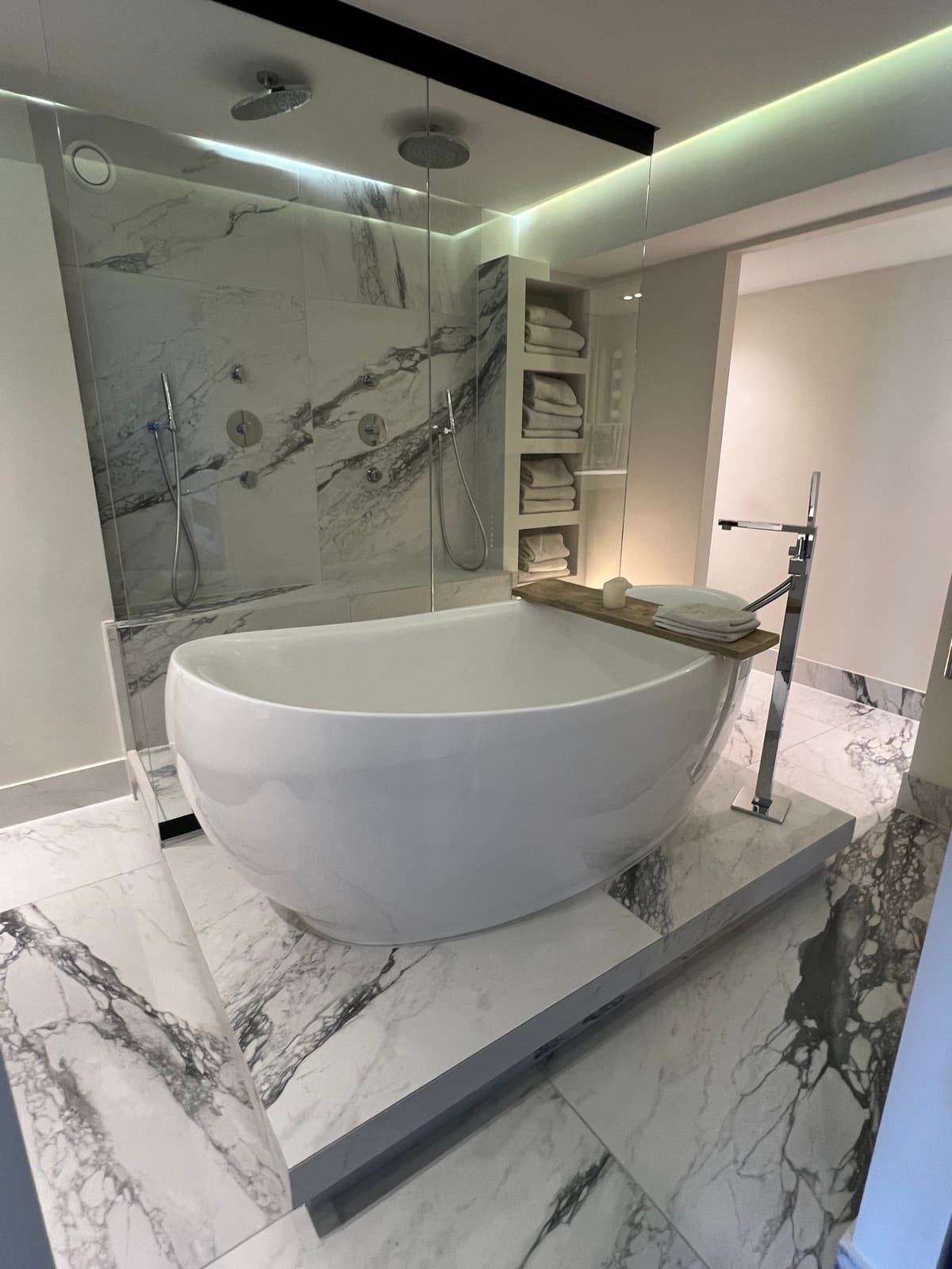 Renovated bathroom finished in warm stone with a curved brass tap
